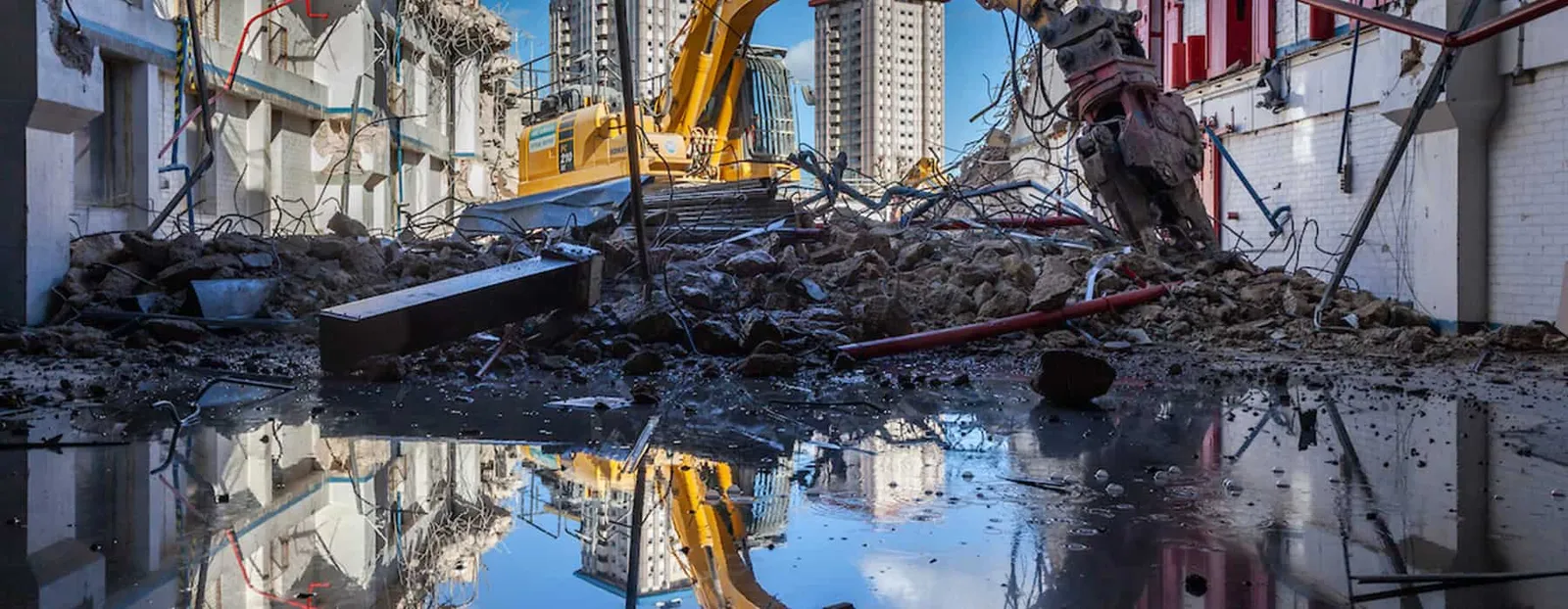 John F Hunt - Demolition waste on ground with excavator in background